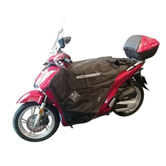 Motocicleta roja con funda protectora y baúl trasero.